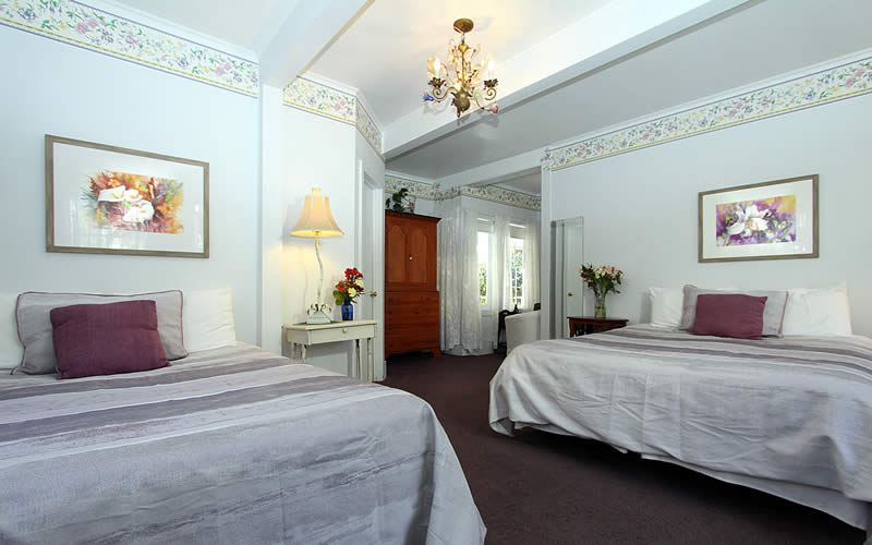 geranium room with two double beds and small sitting area